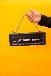 Close-up of a hand holding a sign with a motivational message against a vibrant yellow background.